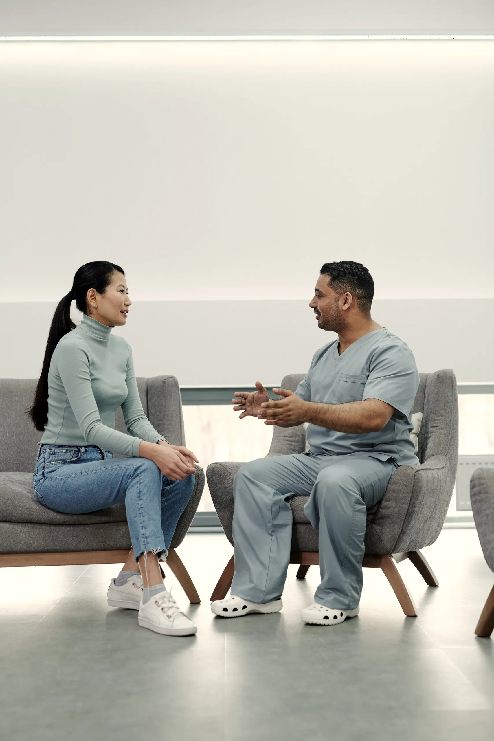 A clinician and a patient talking in comfortable chairs in a bright, calm office.