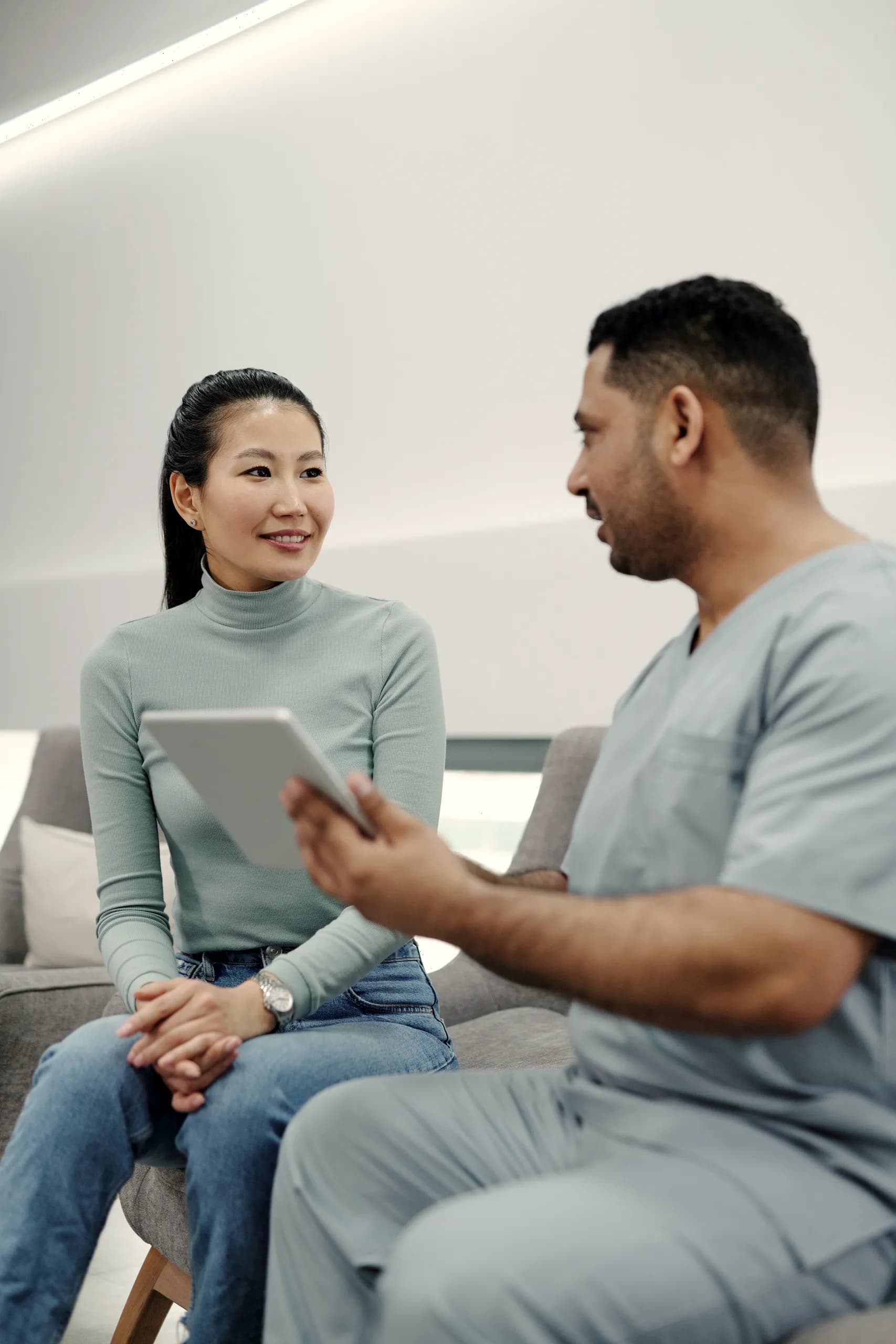 A clinician reviewing results with a smiling patient on a tablet.